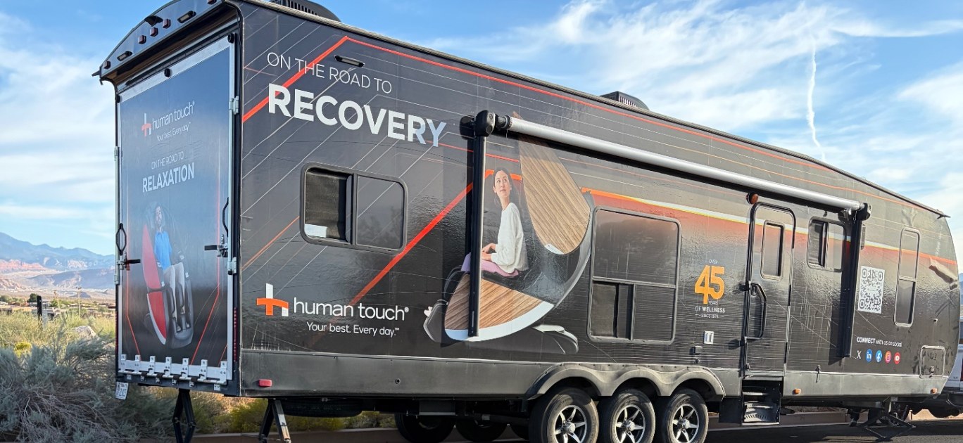 The Human Touch recovery RV, wrapped in On the Road to Recovery graphics, parked with red-rock mesas behind it
